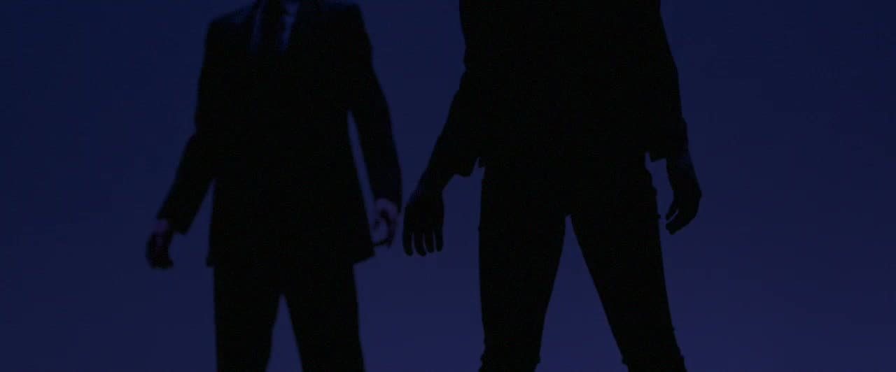Dancers in silhouette against a deep indigo stage backdrop.